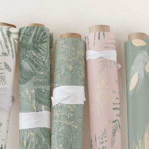 May include: Five rolls of green and gold patterned wrapping paper with white ribbon ties. The patterns include leaves, feathers, and abstract designs.