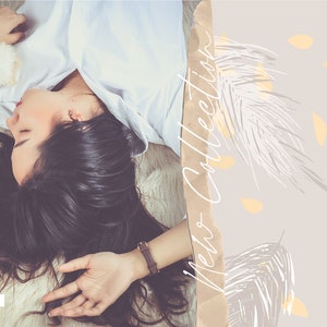 May include: A woman with long dark hair is lying on a white fluffy surface. She is wearing a white shirt and a brown watch. The background is a light gray with a brown and white abstract design and the text "Veto Collection".