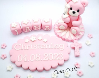 Peut inclure: Décor de gâteau en fondant rose avec un ours en peluche tenant un lapin blanc, une croix et une plaque ovale rose avec le texte "Baptême 04.06.2023" et le nom "JANA" écrit en lettres roses.
