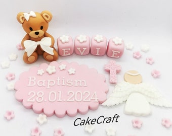 Peut inclure: Ensemble de décorations de gâteau rose et blanc avec un ours en peluche brun, des ailes d'ange blanches, une croix et le nom "Evie" écrit en lettres roses. La décoration comprend également une pancarte rose et blanche qui dit "Bapteme 28.01.2024".