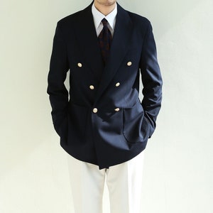 May include: A navy blue double-breasted blazer with gold buttons and a white collared shirt with a patterned tie.