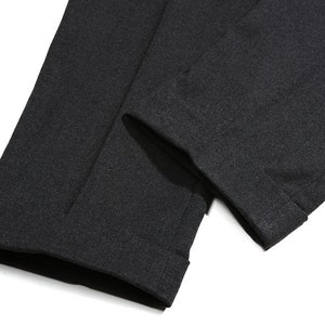 K&ouml;nnte beinhalten: Nahaufnahme des Saums einer schwarzen Hose. Der Stoff ist ein weicher, strukturierter Strick.