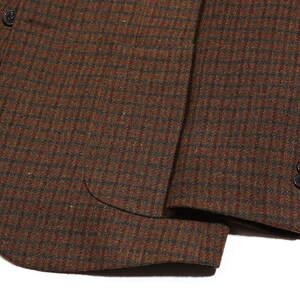 May include: A brown and black plaid blazer with a single button closure and a pocket on the left side. The blazer has a textured fabric and a brown lining.
