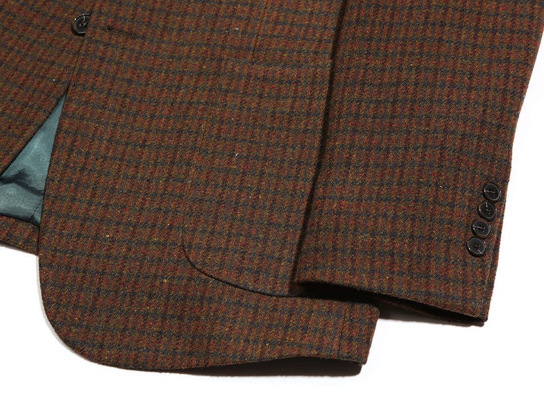 May include: A brown and black plaid blazer with a single button closure and a pocket on the left side. The blazer has a textured fabric and a brown lining.