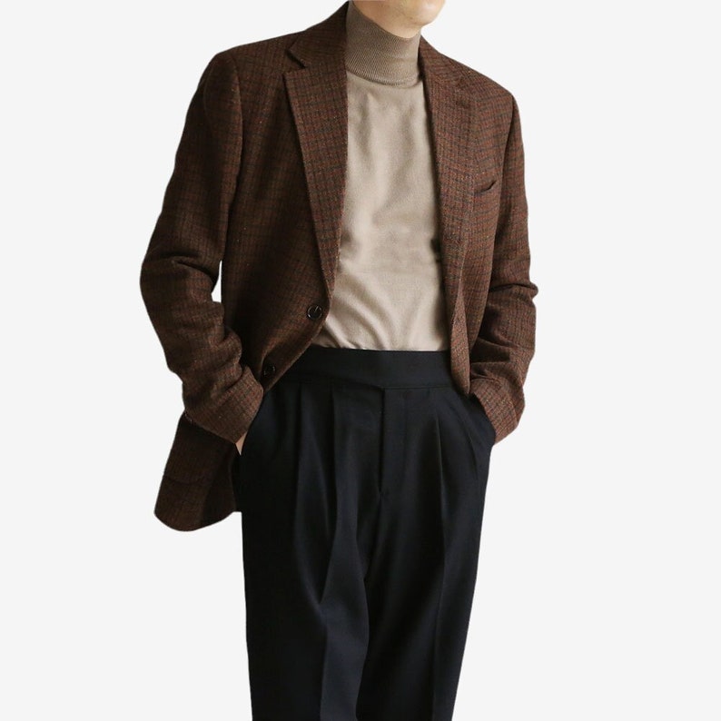 May include: A brown and black plaid blazer with a beige turtleneck sweater and black pants.