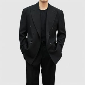 Może przedstawiać: Czarny dwurzędowy blazer z sześcioma guzikami i klapami z wycięciami. Blazer jest połączony z czarnymi spodniami i czarnym t-shirtem. Strój jest klasyczny i formalny.