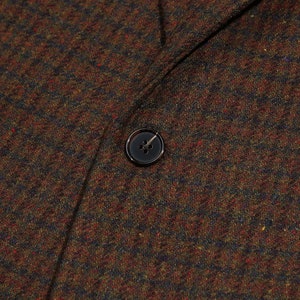 May include: Close-up of a brown, black, and red tweed fabric with a black button.