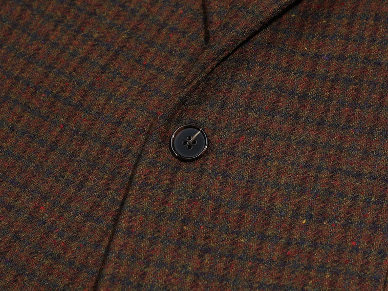 May include: Close-up of a brown, black, and red tweed fabric with a black button.