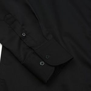 May include: Close-up of a black dress shirt. The image highlights the cuff with three buttons and the buttoned placket. The fabric has a subtle texture. The shirt is a solid black color.