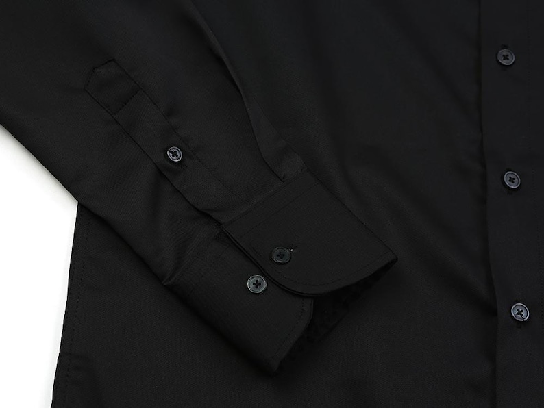 May include: Close-up of a black dress shirt. The image highlights the cuff with three buttons and the buttoned placket. The fabric has a subtle texture. The shirt is a solid black color.