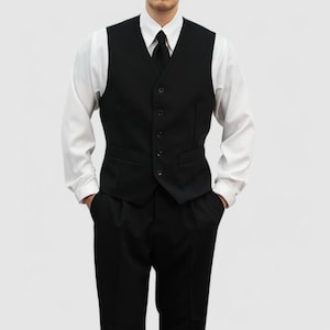 May include: A black vest with a matching black tie and black pants. The vest has a five-button closure and two front pockets. The outfit is paired with a white dress shirt.