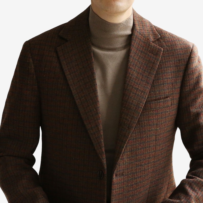 May include: A brown tweed blazer with a checkered pattern. The blazer has a single button closure and a notched lapel.
