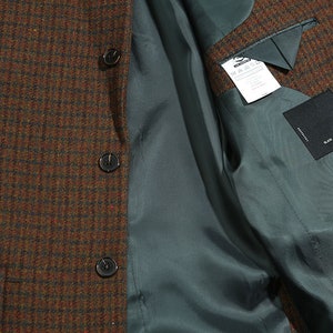 May include: A brown and green plaid blazer with a teal lining. The blazer has three buttons and a pocket on the left side. The lining has a label that says "Black Label" and "Size L".