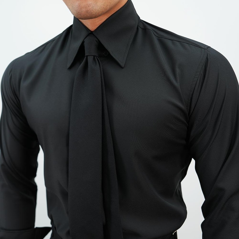 May include: A black dress shirt with a wide collar and a long, draped tie. The shirt is made of a smooth fabric and has long sleeves. The tie is the same color as the shirt.