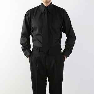 May include: A black long-sleeve shirt with a matching tie and suspenders. The shirt has a classic collar and buttoned cuffs. The pants are black and pleated. The outfit is a formal style.