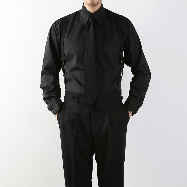 May include: A black long-sleeve shirt with a matching tie and suspenders. The shirt has a classic collar and buttoned cuffs. The pants are black and pleated. The outfit is a formal style.