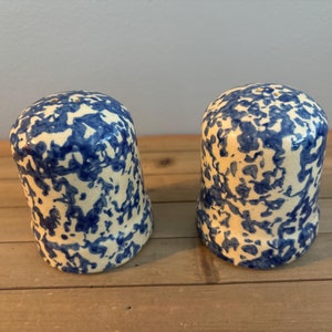 May include: A pair of salt and pepper shakers with a blue and white speckled design.