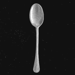 May include: A silver spoon with an oval bowl and a long, slender handle. The spoon has a detailed, embossed pattern on both the bowl and handle, and is set against a black background.