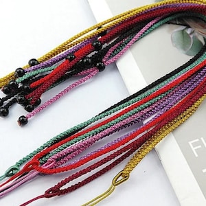 May include: A collection of colorful cords with black beads, perfect for crafting jewelry or macrame projects.