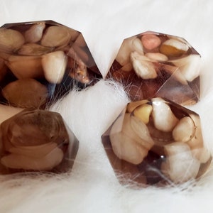 May include: Four clear resin coasters with a geometric shape and embedded stones in shades of brown, white, and beige.