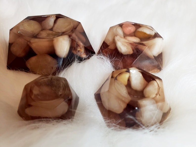 May include: Four clear resin coasters with a geometric shape and embedded stones in shades of brown, white, and beige.