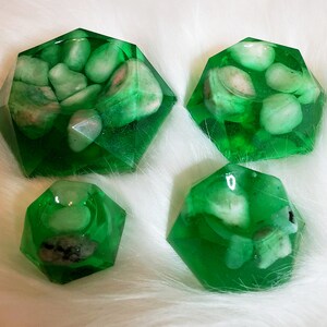 May include: Four green resin dishes with a faceted design, each containing white stones. The dishes are different sizes and shapes.