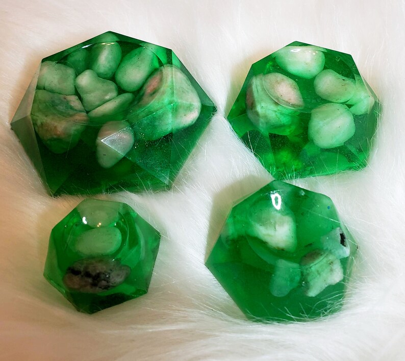 May include: Four green resin dishes with a faceted design, each containing white stones. The dishes are different sizes and shapes.