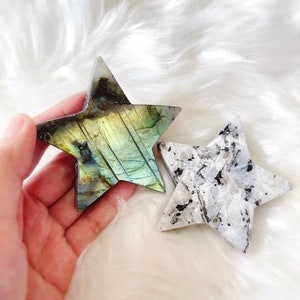 May include: Two star-shaped crystal points, one is a green and blue labradorite, the other is a white and black moonstone.
