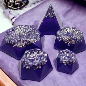 May include: Five purple resin geometric shapes with a sparkly silver glitter finish. The shapes are a pyramid and four different sized octagons.