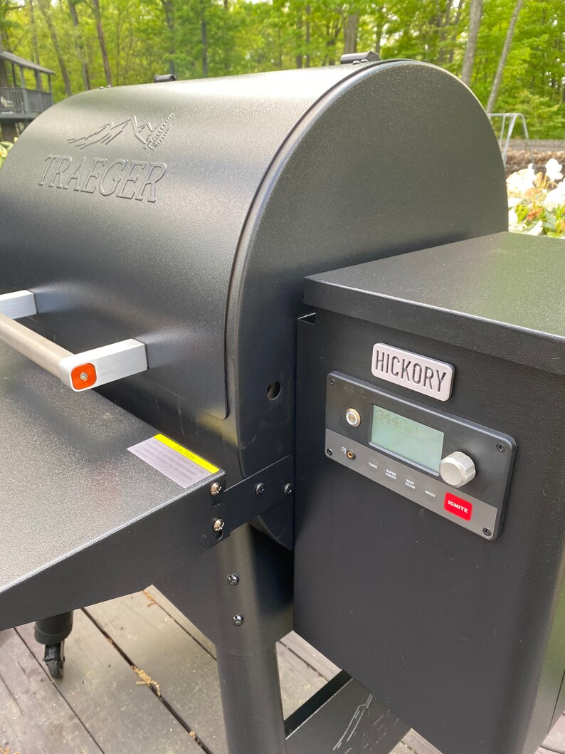May include: A black Traeger wood pellet grill with a digital control panel and a side-mounted wood pellet hopper labelled "Hickory".