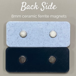 May include: Two rectangular pieces of plastic, one white with black speckles and one black, each with two 8mm ceramic ferrite magnets attached to the back side.