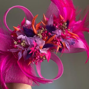 May include: A pink and purple flower hair clip with feathers and a net base.