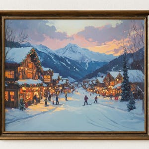 May include: A framed winter landscape painting depicting a snow-covered village nestled in a mountain valley. The artwork features buildings with warm interior lighting, skiers, and a colorful sunset sky. The frame is a warm, golden brown.