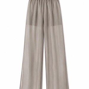 May include: Light taupe wide-leg pants with an elastic waistband. The sheer fabric has vertical lines, creating a subtle striped effect. The pants have a relaxed fit and a flowing silhouette, suitable for casual wear.