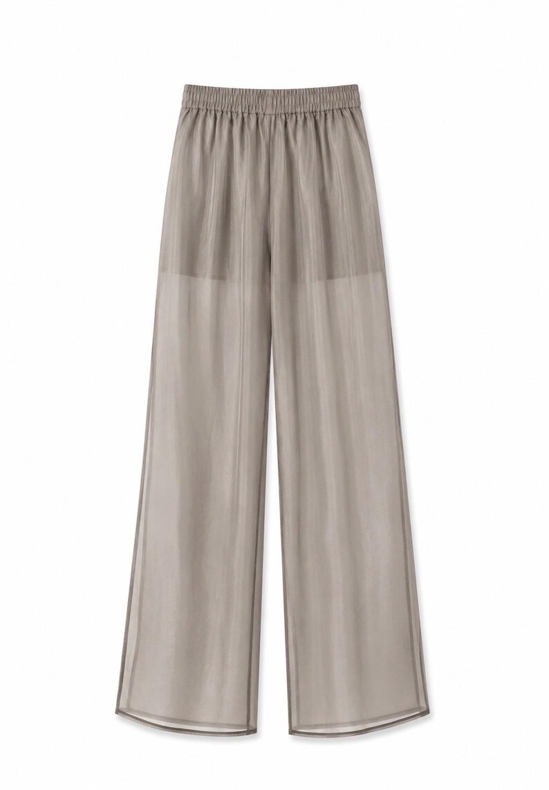 May include: Light taupe wide-leg pants with an elastic waistband. The sheer fabric has vertical lines, creating a subtle striped effect. The pants have a relaxed fit and a flowing silhouette, suitable for casual wear.