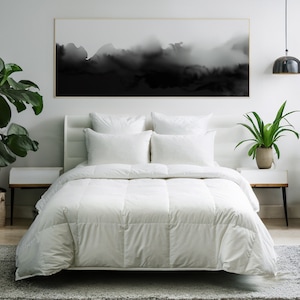 May include: White down comforter on a bed with white bedding and pillows. The bed is in a bedroom with a black and white abstract painting on the wall, a potted plant on a nightstand, and a lamp hanging from the ceiling.