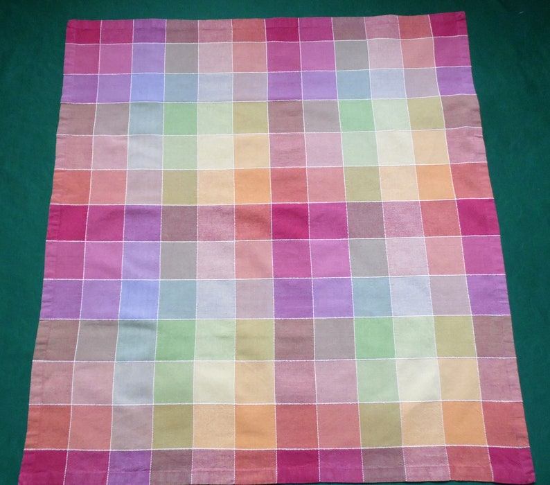 May include: A colorful checkered tablecloth with a variety of pastel colors, including pink, purple, green, yellow, and orange.