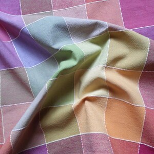 May include: A colorful checkered tablecloth with a rainbow pattern. The fabric is folded and wrinkled, creating a textured look.