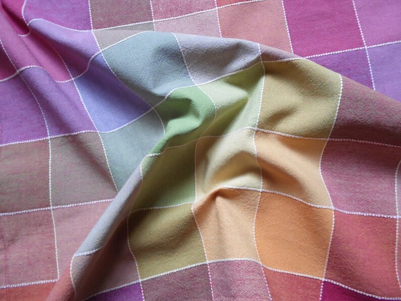 May include: A colorful checkered tablecloth with a rainbow pattern. The fabric is folded and wrinkled, creating a textured look.