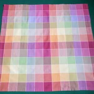 May include: A colorful checkered tablecloth with a variety of pastel colors, including pink, purple, green, and orange.