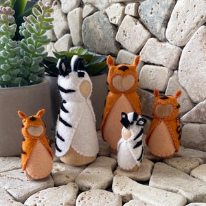 May include: Five felt animal figurines, including a zebra, a tiger, and three orange and white striped tigers. The figurines are standing on a stone surface.