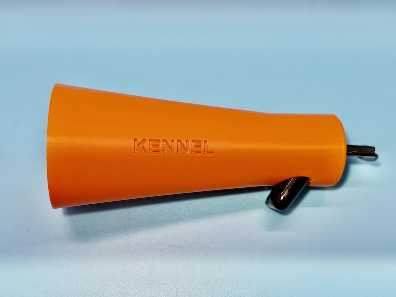 May include: Orange megaphone with the word "KENNEL" embossed on the side. The megaphone has a black handle and a black metal piece attached to the end. The megaphone is on a light blue background.