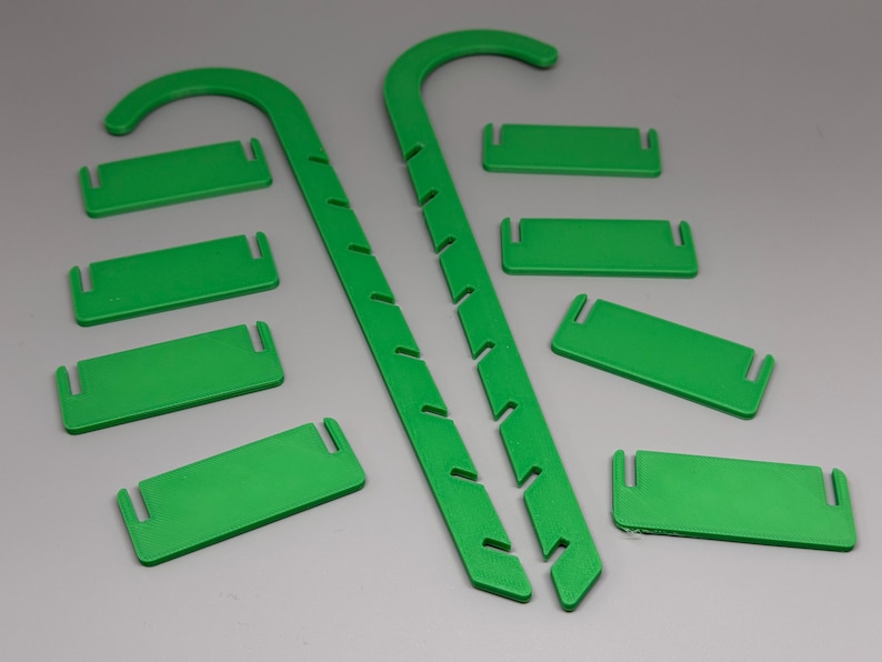 May include: Bright green plant support stakes and matching rectangular clips. The stakes are curved at the top and have notches along the sides. The clips have slots on each end. These items are designed to support plants.