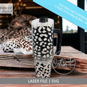 May include: A black and white leopard print tumbler with a black handle. The tumbler is sitting on a wooden surface. "FILE ONLY! NOT A PHYSICAL PRODUCT 2 FILES! Fit for 40oz & 30oz, can be resized." is written on a blue background above the tumbler. "Cest Creative CUSTOM DESIGNS" is written in white on a black circle below the tumbler. "LASER FILE | SVG" is written below the circle.