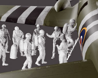Puede incluir: Un grupo de figuras de plástico blanco de paracaidistas, algunos con paracaídas, de pie cerca de un avión verde y blanco. El avión tiene un emblema redondo con un diseño rojo, blanco y azul.