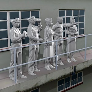 Może przedstawiać: Grupa pięciu posągów osób w mundurach wojskowych stoi na betonowej platformie z barierką. Posągi są jasnoszare i wydają się na coś patrzeć. Tło obejmuje budynek z oknami i pole.