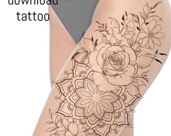 May include: A black and white line drawing tattoo design of a mandala with flowers and leaves. The design is on a woman's thigh.