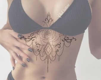May include: A black and white line drawing tattoo design of a rose with a diamond and dangling chains. The design is on a person's chest.