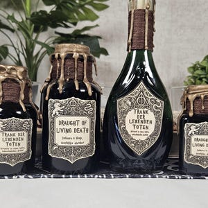 Op de afbeelding: Een verzameling apothekersflessen met etiketten met de tekst "Draught of Living Death" en "Trank der Lebenden Toten". De flessen zijn zwart en groen, met gouden accenten en druipende wasdetails. De etiketten hebben sierlijke ontwerpen.