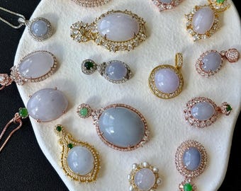 May include: A collection of 16 jade pendants with various settings, including silver, gold, and rose gold. The pendants feature oval and round jade stones with intricate designs.
